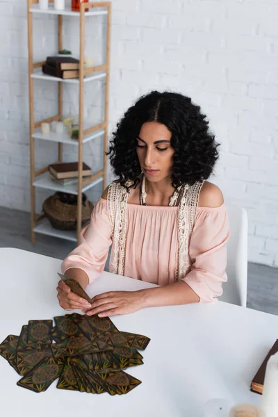 KYIV, UKRAINE - JUNE 29, 2022: young predictor looking at tarot card at home — Photo de stock