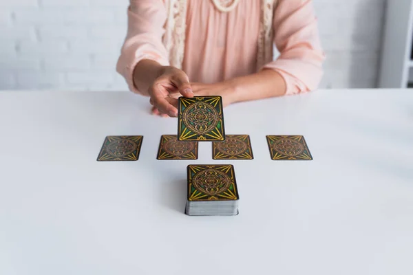 KYIV, UKRAINE - JUNE 29, 2022: cropped view of blurred fortune teller near tarot cards on table - foto de stock