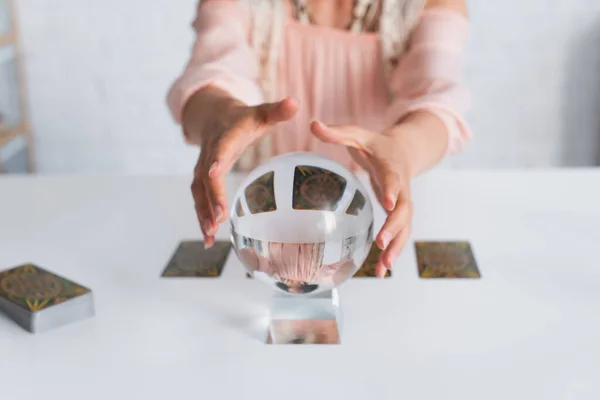 KYIV, UKRAINE - JUNE 29, 2022: selective focus of crystal ball near cropped fortune teller on blurred background — Foto stock