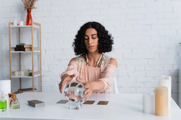 Oracle with closed eyes touching crystal ball near tarot cards — Stock Photo