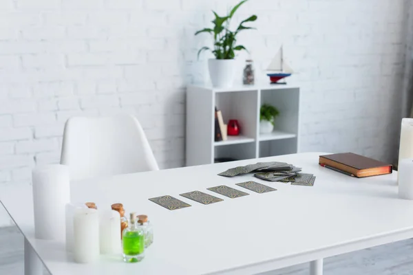 KYIV, UKRAINE - JUNE 29, 2022: tarot cards near prediction book and candles on white table — Stock Photo