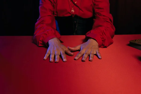 Cropped view of medium with hands on red table isolated on black — Stock Photo
