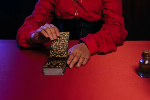 KYIV, UKRAINE - JUNE 29, 2022: partial view of woman predicting on tarot cards on table isolated on black — Stock Photo