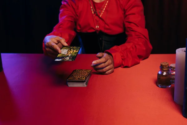 KYIV, UKRAINE - JUNE 29, 2022: cropped view of blurred predictor with tarot cards on black table isolated on white — Stock Photo