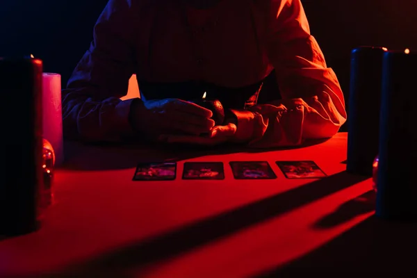 KYIV, UKRAINE - JUNE 29, 2022: cropped view of oracle holding burning candle near tarot cards isolated on black — Fotografia de Stock