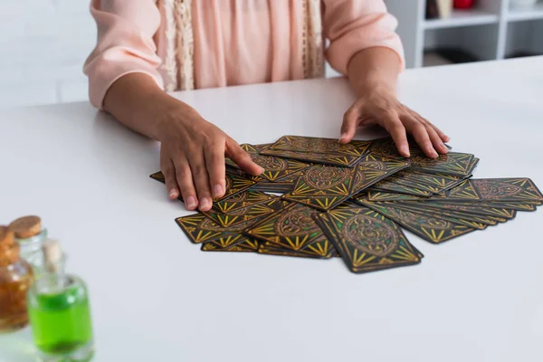 KYIV, UKRAINE - JUNE 29, 2022: cropped view of predictor near tarot cards and blurred bottles with essential oils — Foto stock