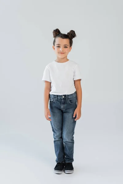 Full length of cheerful girl with sparkling glitter stars on cheeks looking at camera on grey — Stock Photo