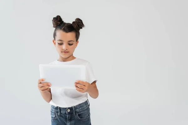 Adorable girl with glitter stars on cheeks using digital tablet isolated on grey — Photo de stock