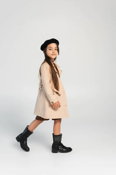 Повна довжина милої дівчини в стильному траншеї пальто і берет ходьби на сірому — стокове фото