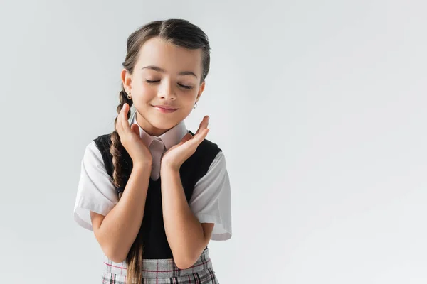 Portrait of happy schoolgirl with closed eyes gesturing isolated on grey — Photo de stock