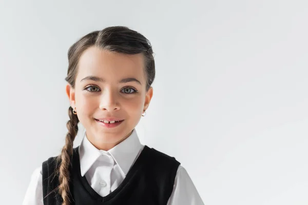 Portrait of happy schoolgirl in white shirt and vest looking at camera isolated on grey — Stockfoto