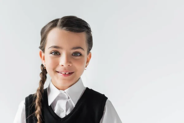 Portrait of happy schoolgirl in white shirt and vest looking at camera isolated on grey — Stock Photo