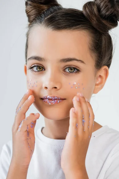 Portrait of cute kid with sparkling glitter stars on face and lips looking at camera isolated on white — Photo de stock