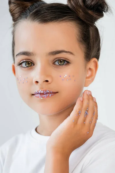 Portrait of cute girl with sparkling glitter stars on lips and cheeks looking at camera isolated on white — Foto stock