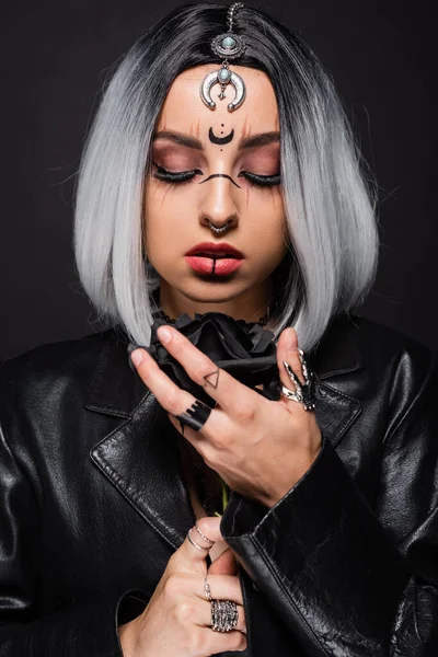 Frau mit Hexen-Stil Make-up und Accessoires hält dunkle Rose isoliert auf schwarz — Stockfoto