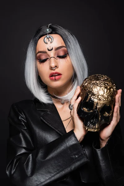 Sexy witch style woman with ash blonde hair holding golden skull isolated on black — Stock Photo