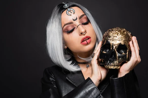 Seductive ash blonde woman with halloween makeup and creepy skull isolated on black — Stock Photo