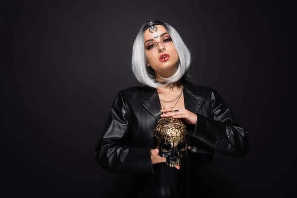 Hexe Stil Frau mit aschblonden Haaren hält goldenen Totenkopf isoliert auf schwarz — Stockfoto