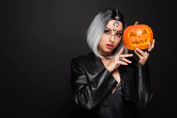 Ash blonde woman in witch costume holding jack o lantern isolated on black — Stock Photo