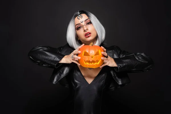 Femme sexy en costume de sorcière posant avec Jack o lanterne isolée sur noir — Photo de stock
