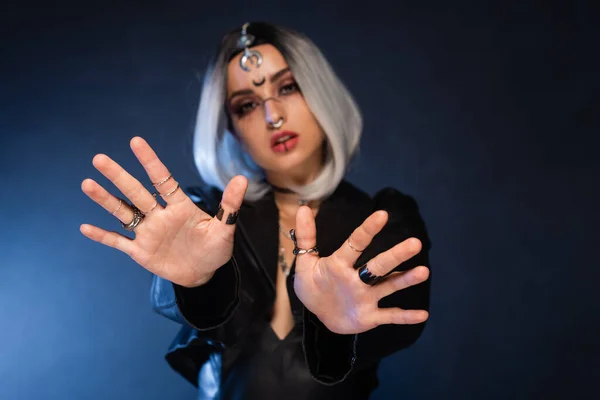 Femme floue dans le maquillage de sorcière avec les mains tendues sur fond noir et bleu — Photo de stock