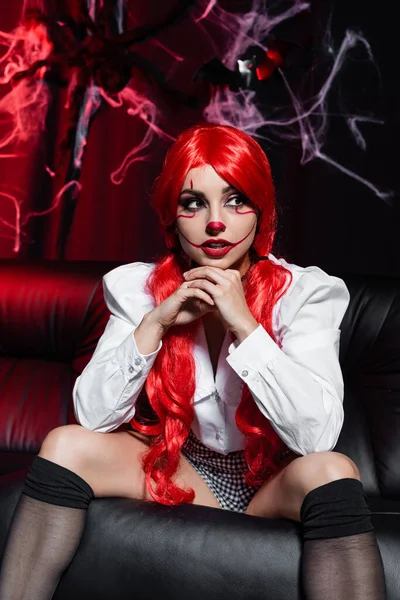 Sexy pelirroja mujer con halloween maquillaje sentado en oscuro fondo cerca de spiderweb - foto de stock