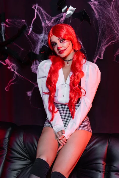 Redhead woman with ponytails and clown makeup looking at camera on black background with spiderweb — Stock Photo