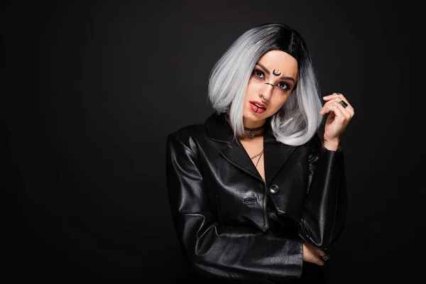 Young woman in leather jacket and with halloween makeup looking at camera isolated on black — Stock Photo