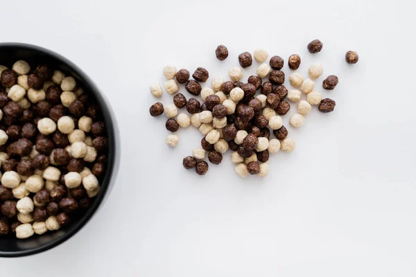 Top view of cereal balls with chocolate and vanilla flavors near bowl isolated on white — Stock Photo