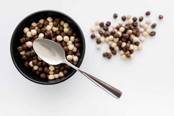 Vista dall'alto di palline di cereali con aromi di cioccolato e vaniglia in ciotola con cucchiaio isolato su bianco — Foto stock