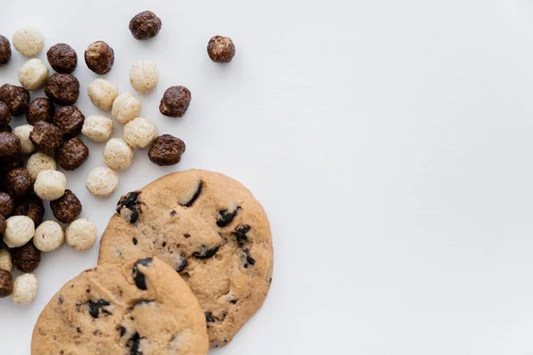 Vista superior de bolas de cereais com sabores de baunilha e chocolate perto de biscoitos saborosos isolados em branco — Fotografia de Stock