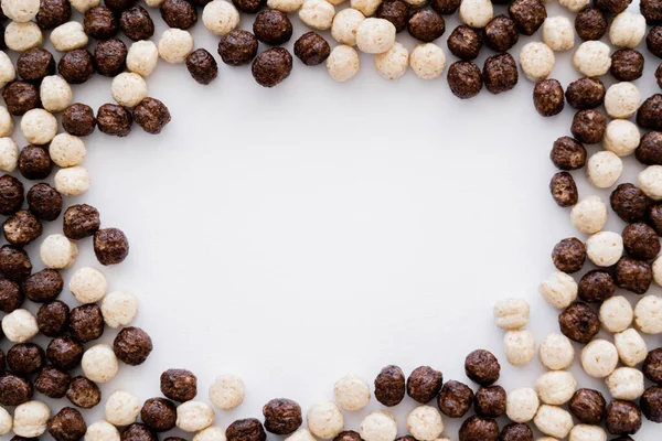 Vista dall'alto della cornice fatta di palline di cereali con aromi di vaniglia e cioccolato isolati su bianco — Foto stock