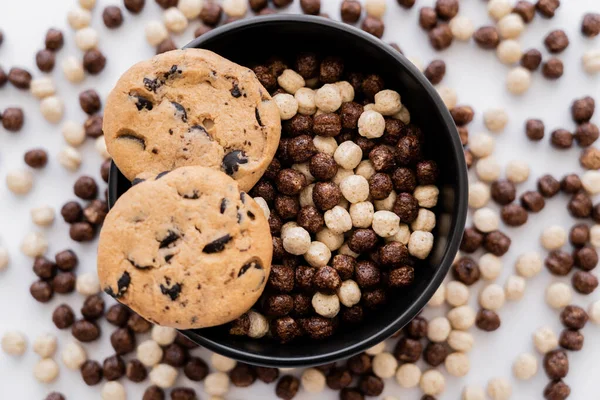 Top view of chocolate chip cookies on top of bowl with cereal balls isolated on white — Stock Photo