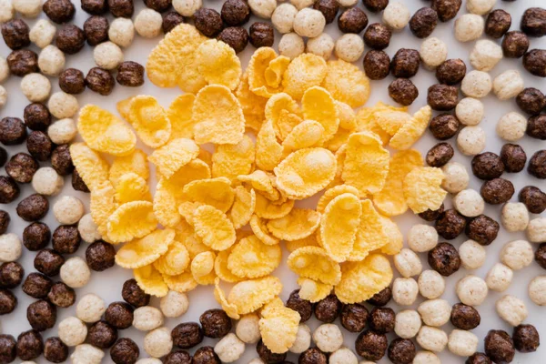 Top view of corn flakes and cereal balls with vanilla and chocolate flavors on white — Stock Photo