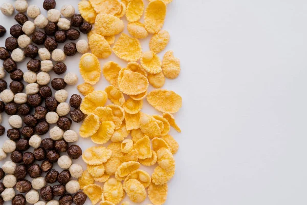 Vista superior de bolas de cereais com sabores de baunilha e chocolate perto de flocos de milho isolados em branco — Fotografia de Stock