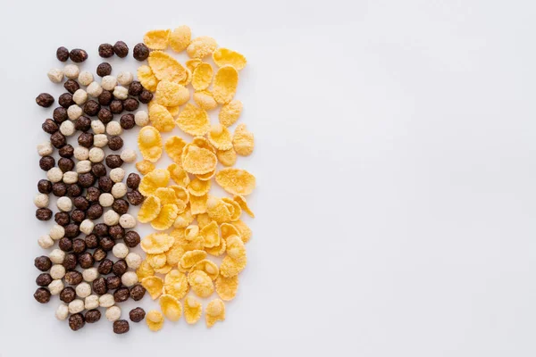 Vista dall'alto di palle di cereali con diversi sapori vicino fiocchi di mais isolati su bianco — Foto stock