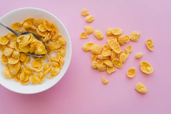 Top view of bowl with corn flakes and organic milk on pink background — Stock Photo