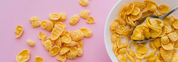 Top view of bowl with corn flakes and organic milk on pink background, banner — Stock Photo