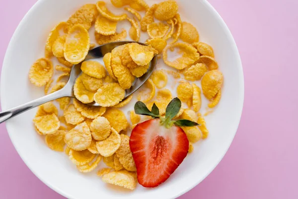 Draufsicht auf Schüssel mit Cornflakes und frischen Erdbeeren auf rosa Hintergrund — Stockfoto