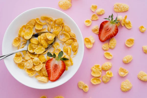 Top view of bowl with corn flakes and organic strawberry on pink background — Stock Photo