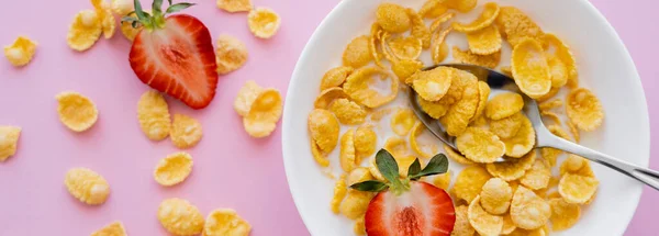 Top view of bowl with corn flakes and organic strawberries on pink background, banner — Stock Photo