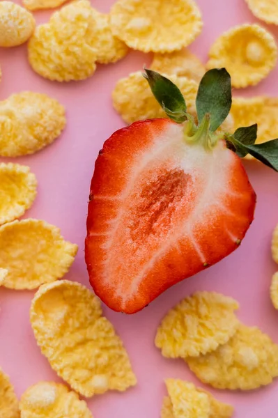 Half of fresh sliced strawberry around crispy corn flakes on pink — Stock Photo