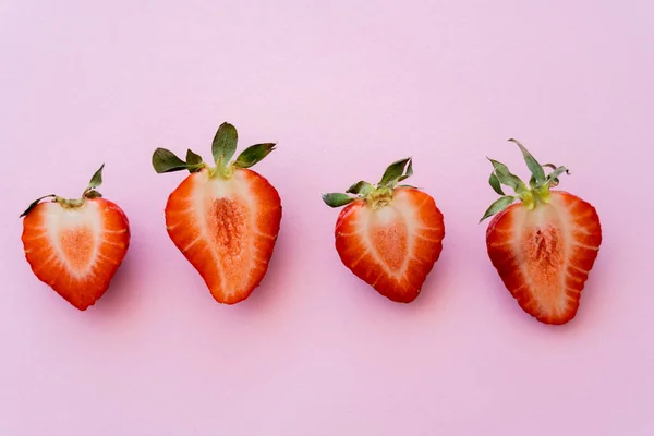 Flat lay of red sliced strawberries in row isolated on pink with copy space — Stock Photo