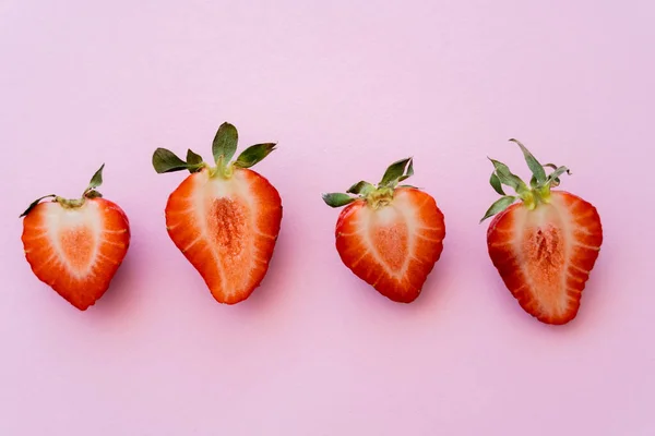 Tendido plano de fresas en rodajas rojas en fila aislado en rosa con espacio de copia - foto de stock