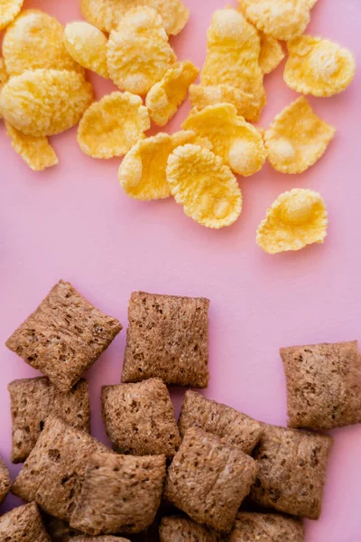 Vista superior de las bocanadas de cereales de desayuno y copos de maíz crujientes aislados en rosa - foto de stock