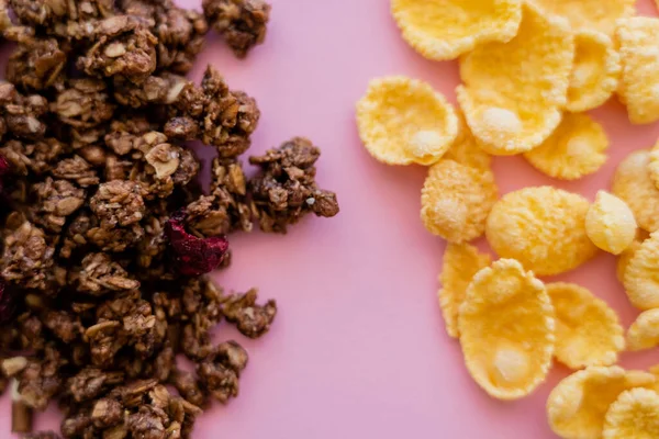 Top view of crispy corn flakes and crunchy granola isolated on pink — Stock Photo