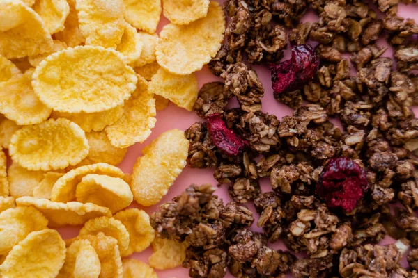 Vista de cerca de copos de maíz crujientes y granola crujiente en rosa - foto de stock