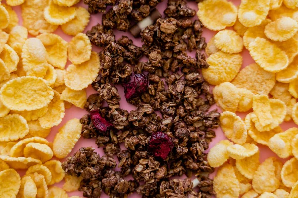 Vista de cerca de copos de maíz crujientes y sabrosa granola en rosa - foto de stock