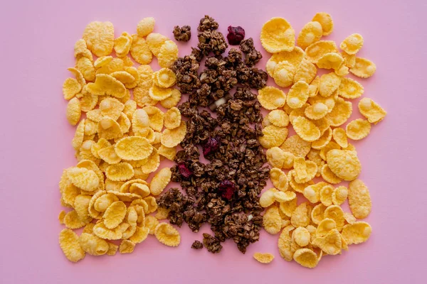 Vista plana de hojuelas de maíz crujiente y sabrosa granola aislado en rosa - foto de stock