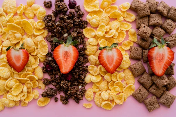 Vista superior de morangos frescos em cereais de pequeno-almoço variados e granola isolado em rosa — Fotografia de Stock